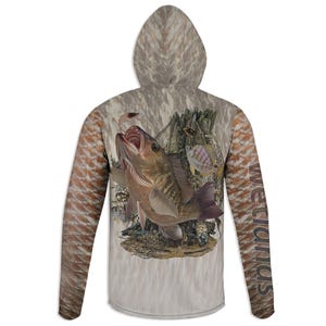 May include: A hooded long-sleeve shirt with a fish and aquatic life design. The shirt features a large fish with an open mouth, surrounded by other fish and a shrimp. The sleeves have a brown and orange pattern, and the word "Wetlands" is printed vertically.