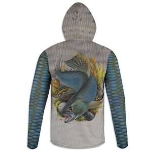 May include: A hooded sweatshirt featuring a detailed illustration of a blue fish with its mouth open, surrounded by aquatic plants and rocks. The sleeves have a blue scale pattern, and the hood has a textured, fish-like pattern.