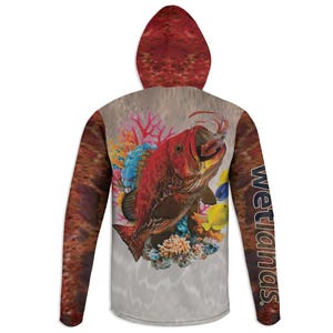 May include: A hooded sweatshirt featuring a vibrant illustration of a red fish with an open mouth, surrounded by coral and other marine life. The sleeves and hood have a textured pattern, and the word "Wetlands" is printed on the sleeve.