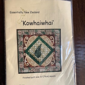 May include: A package featuring a quilt design with the text "Essentially New Zealand" and "Kowhaiwhai". The quilt design is a square with a central green fern design, surrounded by geometric patterns. The finished quilt size is 31 inches (79cm) square.