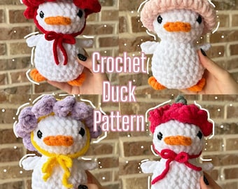 May include: Four white crochet duck plushies with orange beaks and feet. Each duck wears a different colored hat: red with a bow, light pink, purple with a yellow tie, and red with a bow. The text Crochet Duck Pattern is centered in the image.