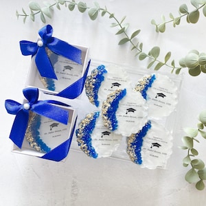 May include: Blue and gold graduation party favors with the text "Thank you for celebrating with me Dr. Amber Person, OTD 06.28.2023"