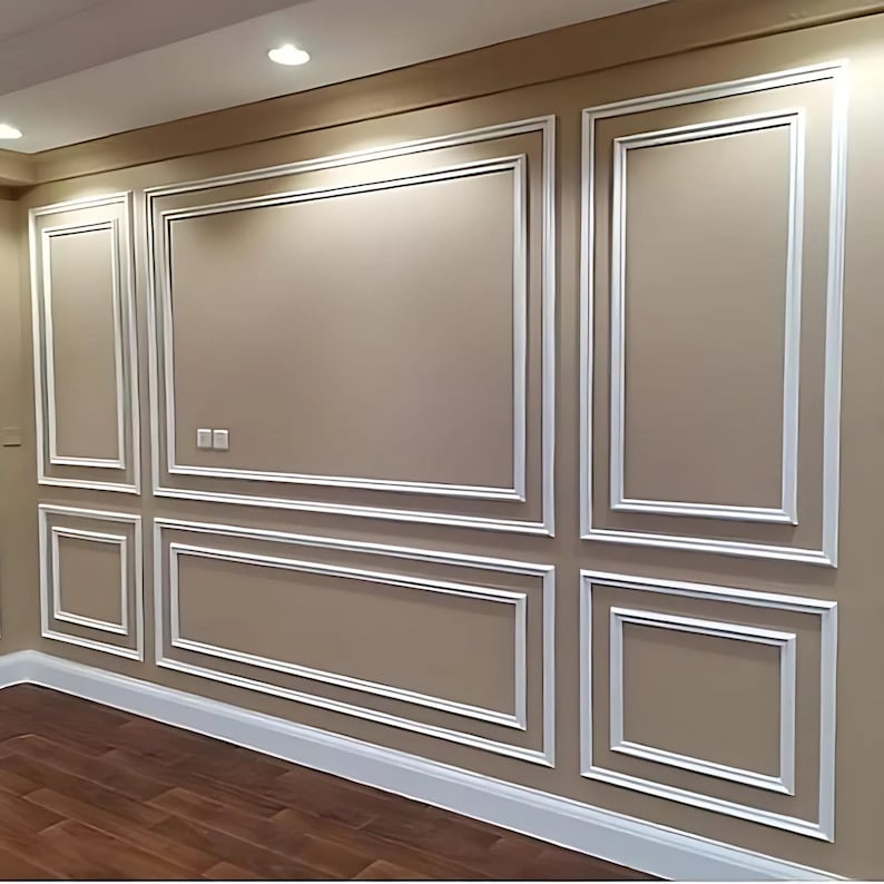 May include: A beige wall featuring white decorative molding trim arranged in rectangular panels. The wall includes a large central horizontal rectangle, two tall vertical rectangles on the sides, and two smaller horizontal rectangles below.