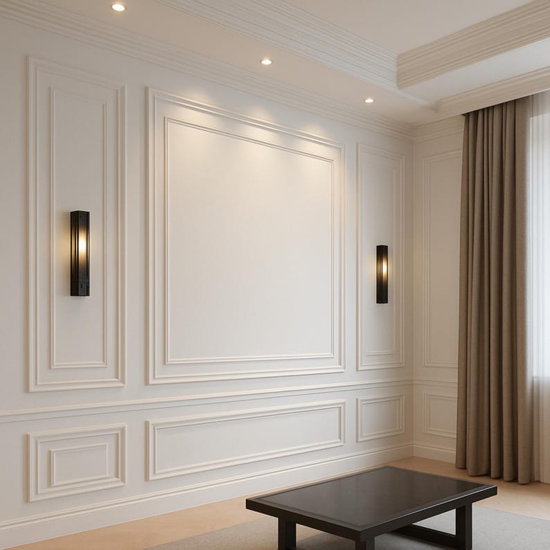 Pode incluir: Uma parede branca com molduras retangulares e duas arandelas pretas verticais que emitem luz quente. Uma mesa de centro retangular marrom escura est&aacute; em primeiro plano e cortinas bege est&atilde;o penduradas no lado direito da sala.