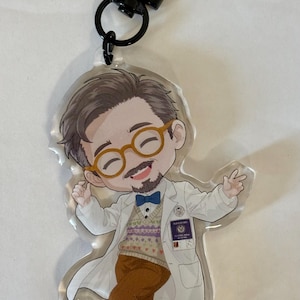 May include: An acrylic keyring featuring a cartoon character with brown hair, a beard, and round glasses. The character wears a white lab coat, a patterned sweater vest, a blue bow tie, and brown trousers, with a small ID badge on the coat.