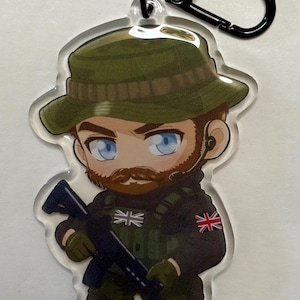 May include: An acrylic keyring featuring a cartoon soldier with a beard, blue eyes, and a green boonie hat. The character wears a black tactical uniform with a green vest, a Union Jack patch on the shoulder, and a small flag on the chest, holding a rifle.