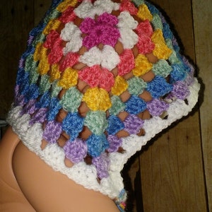 Pu&ograve; includere: Un cappello bianco all'uncinetto con un motivo a quadrato della nonna arcobaleno. Il cappello ha un'ampia tesa ed &egrave; realizzato con un filato morbido.