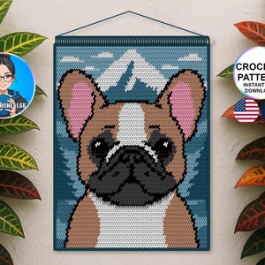 May include: Crocheted wall hanging featuring a French Bulldog. The dog has brown, white, and black details with pink ears. The background is blue with a mountain and cloud design. The text "CROCHET PATTERN INSTANT PDF DOWNLOAD" is visible.