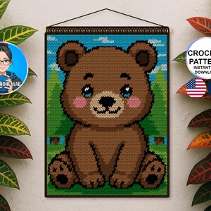 Peut inclure: Une tenture murale en crochet représentant un ours brun sur fond de ciel bleu et d'herbe verte. L'ours a les yeux bleus et les joues roses. Le texte "CROCHET PATTERN INSTANT PDF DOWNLOAD" est dans un cercle avec les drapeaux américain et français.