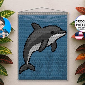 May include: A crochet wall hanging featuring a pixelated dolphin in shades of gray and white against a blue background. The dolphin is leaping, with a detailed fin and tail. The design is framed and ready to hang. The image includes the text "CROCHET PATTERN INSTANT PDF DOWNLOAD".