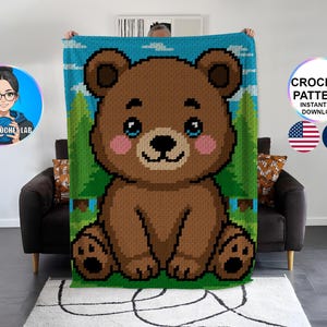 Peut inclure: Une couverture au crochet représentant un ours brun sur un fond de ciel bleu et d'arbres verts. La couverture présente un grand ours souriant avec des joues roses et des yeux bleus. Le texte "CROCHET PATTERN INSTANT PDF DOWNLOAD" est visible, ainsi que les drapeaux américain et français.