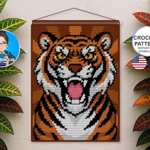 Peut inclure: Une tenture murale au crochet représentant la tête d'un tigre avec des détails orange, noirs, blancs et roses. Le tigre rugit, la gueule ouverte. La tenture est marron et possède une baguette en bois en haut. Le texte "CROCHET PATTERN INSTANT PDF DOWNLOAD" est visible.