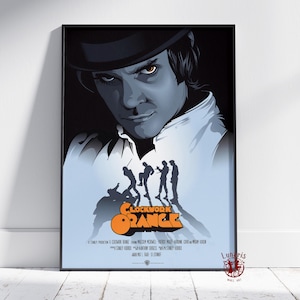 May include: Framed poster of the film "A Clockwork Orange." The artwork features a man in a bowler hat, with the film's title in orange and silhouettes of figures. The poster is in a black frame, suitable for wall art.