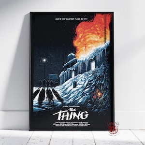 Puede incluir: Un póster de película vertical de The Thing de John Carpenter que muestra un paisaje nevado y oscuro con un edificio en llamas, carámbanos y cuatro figuras que proyectan largas sombras. El texto dice: MAN IS THE WARMEST PLACE TO HIDE y THE THING.