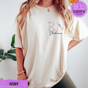 a woman wearing a white t - shirt with a flower embroidered on it