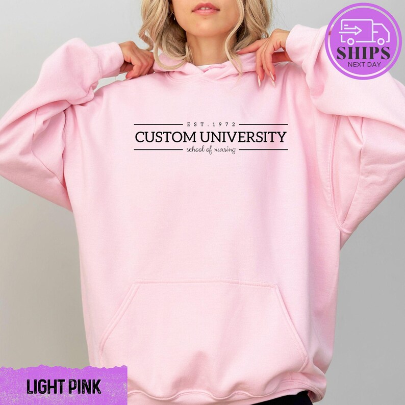 a woman wearing a pink hoodie that says custom university