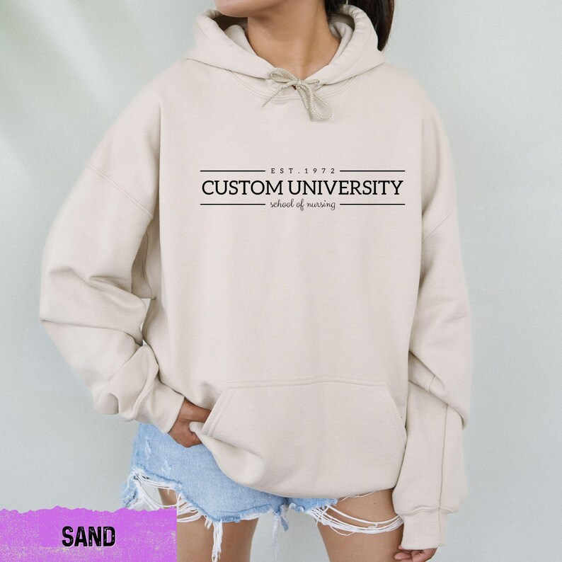 a woman wearing a white hoodie with the words custom university printed on it