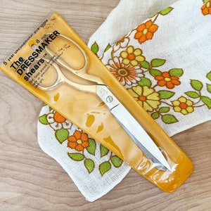 May include: Gold-plated dressmaker shears in a clear plastic package with a yellow background. The package has the text "The Dressmaker shears" and "5 year unconditional guarantee".