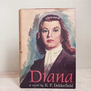 May include: A vintage book cover with a painting of a woman with red hair. The woman is wearing a white collared shirt and a dark purple jacket. The title of the book is "Diana" and the author is "R.F. Deldferfield".