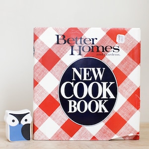 May include: A red and white checkered cookbook titled "Better Homes and Gardens New Cookbook".