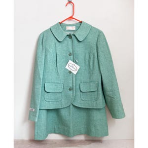 May include: A mint green skirt suit with a peter pan collar, button closure, and two pockets on the jacket. The suit has a tag that says "La Petite"