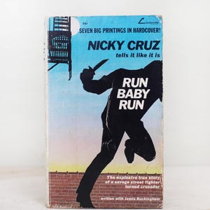 May include: A book cover with a silhouette of a person running with a knife in their hand. The title of the book is "Run Baby Run" and the author is Nicky Cruz. The book cover is blue and pink with a brick wall at the bottom.