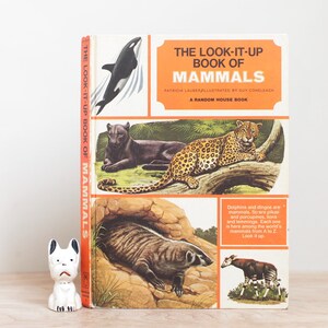 May include: A vintage orange and yellow book titled "The Look-It-Up Book of Mammals" with illustrations of a leopard, a badger, an okapi, and a killer whale. The book is a Random House publication.