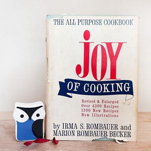 May include: A vintage cookbook titled "The All Purpose Cookbook Joy of Cooking" by Irma S. Rombauer and Marion Rombauer Becker. The cover is white with red and blue lettering.