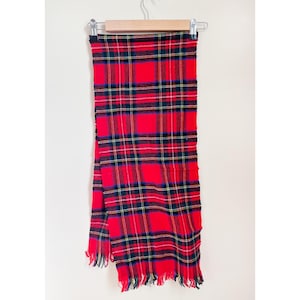 May include: Red and black plaid scarf with fringed edges.