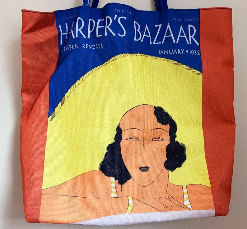 May include: A red, white, and blue tote bag with a vintage Harper's Bazaar magazine cover featuring a woman with dark hair and a yellow hat. The cover reads "Harper's Bazaar" and "January 1932".