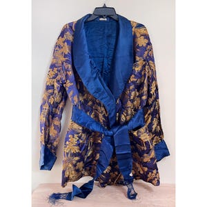 May include: A blue and gold patterned robe with a satin collar and sash. The robe has a tassel on the sash.