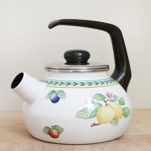 May include: White enamel teapot with a black handle and lid. The teapot has a floral design with fruit and leaves in shades of green, yellow, red, and blue.