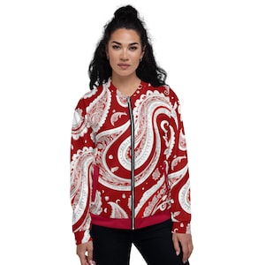 Può includere: Una giacca bomber rossa con un motivo paisley bianco. La giacca ha una chiusura a zip e un colletto, polsini e orlo a coste.