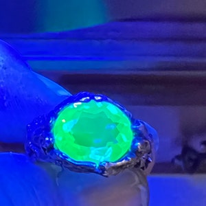 May include: A silver ring with a large, bright green gemstone. The ring is set in a textured, organic-looking band.