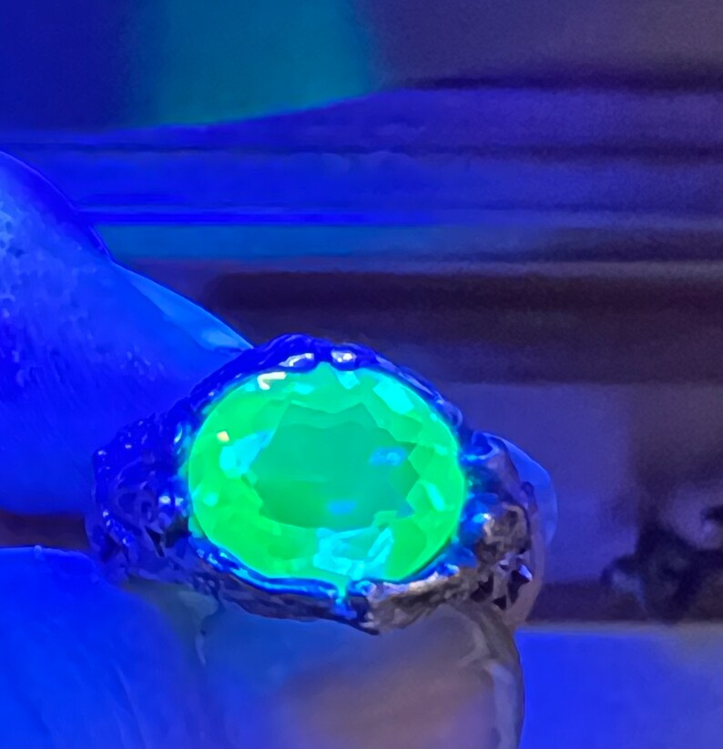 May include: A silver ring with a large, bright green gemstone. The ring is set in a textured, organic-looking band.