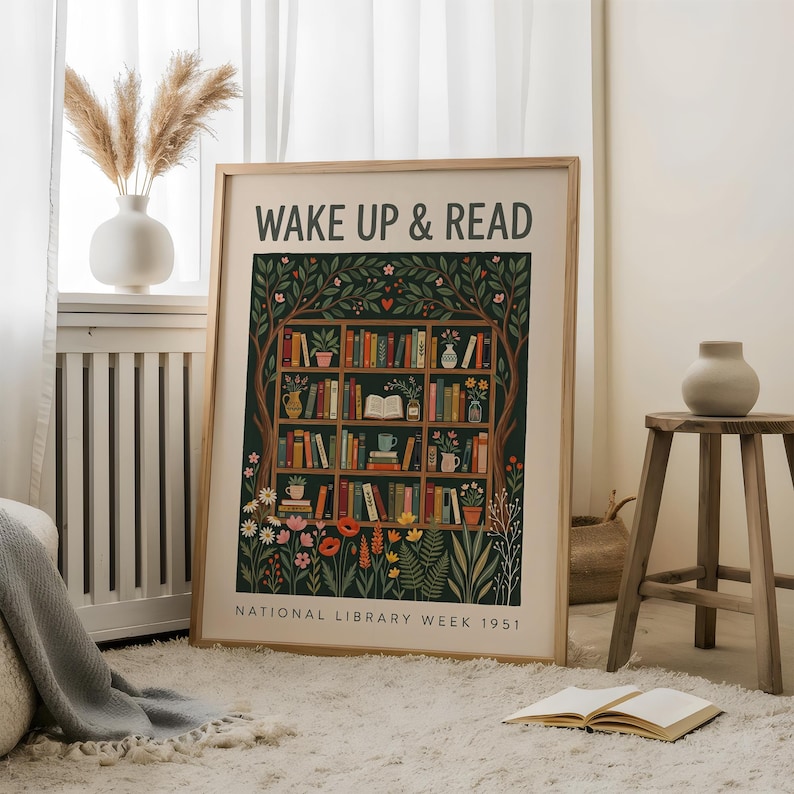 May include: A framed art print featuring the words "WAKE UP & READ" above a colourful illustration of a bookshelf filled with books, plants, and flowers. The print is set against a dark green background and includes the text "NATIONAL LIBRARY WEEK 1951".