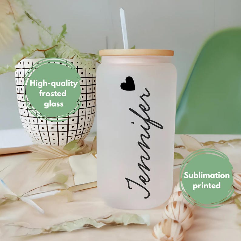 K&ouml;nnte beinhalten: Ein gefrosteter Glasbecher mit Bambusdeckel und Strohhalm. Der Becher hat ein Herz und den Namen "Jennifer" aufgedruckt. Der Becher ist im Sublimationsverfahren bedruckt.
