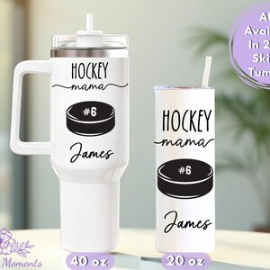 May include: Two white tumblers with black text and graphics. The larger tumbler has a handle and holds 40 oz. The smaller tumbler holds 20 oz. Both say "HOCKEY mama" with a hockey puck graphic and the name "James".