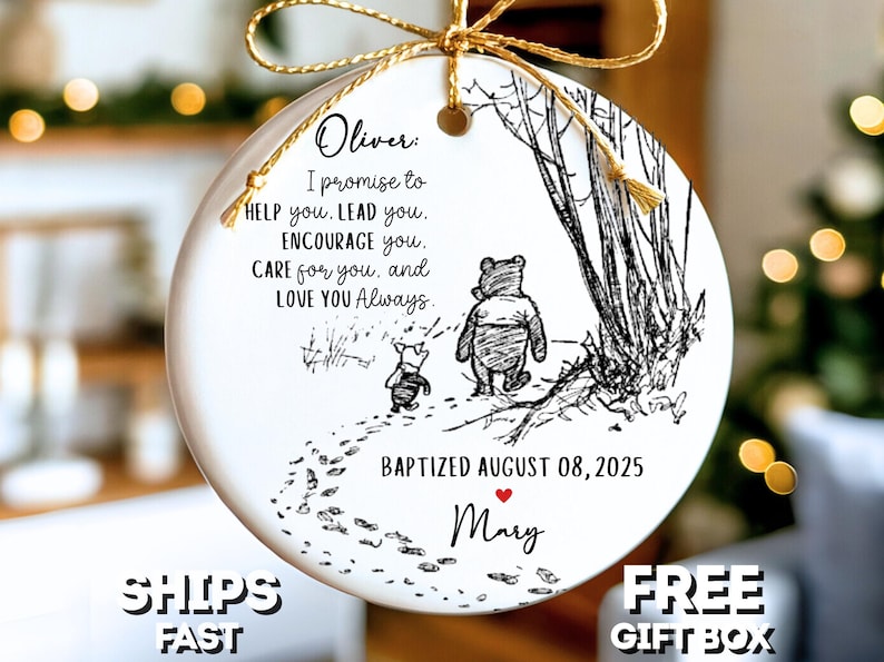 May include: A white ceramic Christmas ornament with a gold ribbon. It features a Winnie the Pooh illustration and text: "Oliver: I promise to help you..." and "Baptized August 08, 2025 Mary."