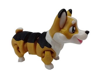 May include: A plastic toy corgi dog with a segmented body. The dog has a white face, chest, and paws, with tan and black markings. Its ears are black-tipped, and it has a pink tongue.