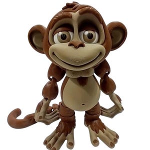 May include: A brown and beige articulated monkey figurine with a smiling expression. The toy monkey has large eyes, a tail, and jointed limbs. The figurine is designed to stand upright.
