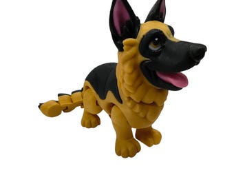 May include: A German Shepherd dog figurine with a black and tan color scheme. The figure features a black muzzle, pointed ears with pink inner details, and a pink tongue. The body is articulated with segmented parts, including a tail and legs.
