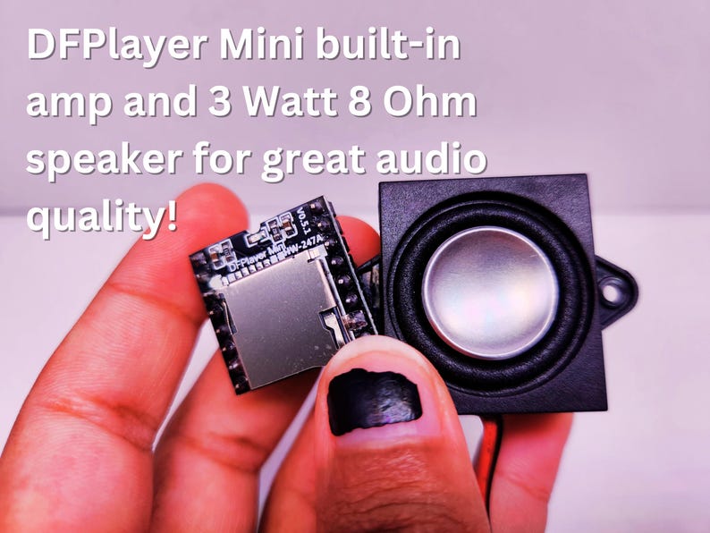 Close-up of a hand holding a DFPlayer Mini module and a 3 Watt 8 Ohm speaker side by side. The DFPlayer Mini features a built-in amplifier. Overlaid text reads 'DFPlayer Mini built-in amp and 3 Watt 8 Ohm speaker for great audio quality!