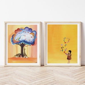 Puede incluir: Dos ilustraciones enmarcadas. La primera muestra un &aacute;rbol colorido con manzanas rojas y dos jirafas debajo. La segunda muestra una ni&ntilde;a con un vestido marr&oacute;n sobre un fondo amarillo con mariposas de colores volando a su alrededor.