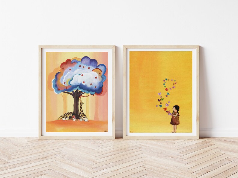 Puede incluir: Dos ilustraciones enmarcadas. La primera muestra un &aacute;rbol colorido con manzanas rojas y dos jirafas debajo. La segunda muestra una ni&ntilde;a con un vestido marr&oacute;n sobre un fondo amarillo con mariposas de colores volando a su alrededor.