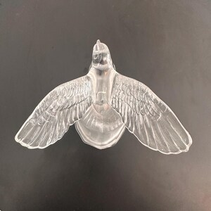 Puede incluir: Una figurita de paloma de vidrio transparente con las alas extendidas. La paloma es un s&iacute;mbolo de paz y esperanza.