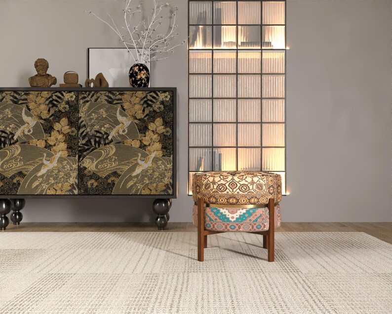 a modern living room with a black and gold cabinet, a patterned armchair, and a glass-paneled divider.