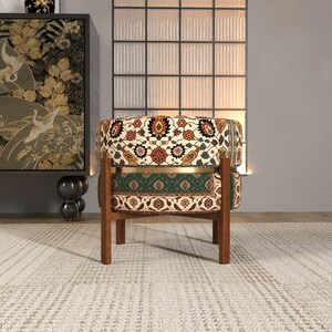 a colorful, patterned chair with a wooden frame, placed on a white rug in a minimalist living room setting.