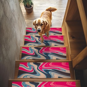 May include: A golden retriever dog on a wooden staircase with decorative stair treads. The treads feature a vibrant abstract design in shades of pink, blue, black, and beige. A potted plant is visible at the top of the stairs.