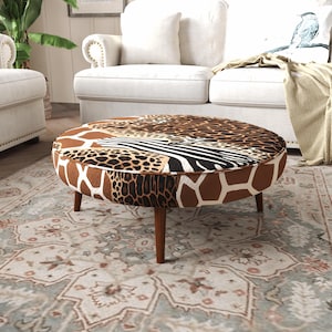 Könnte beinhalten: Ein runder Hocker mit einem Patchwork aus Tiermustern, darunter Giraffenflecken, Leopardenflecken und Zebrastreifen. Das Möbelstück steht auf vier konischen Holzbeinen und hat eine weiße Paspelierung entlang der oberen Kante.